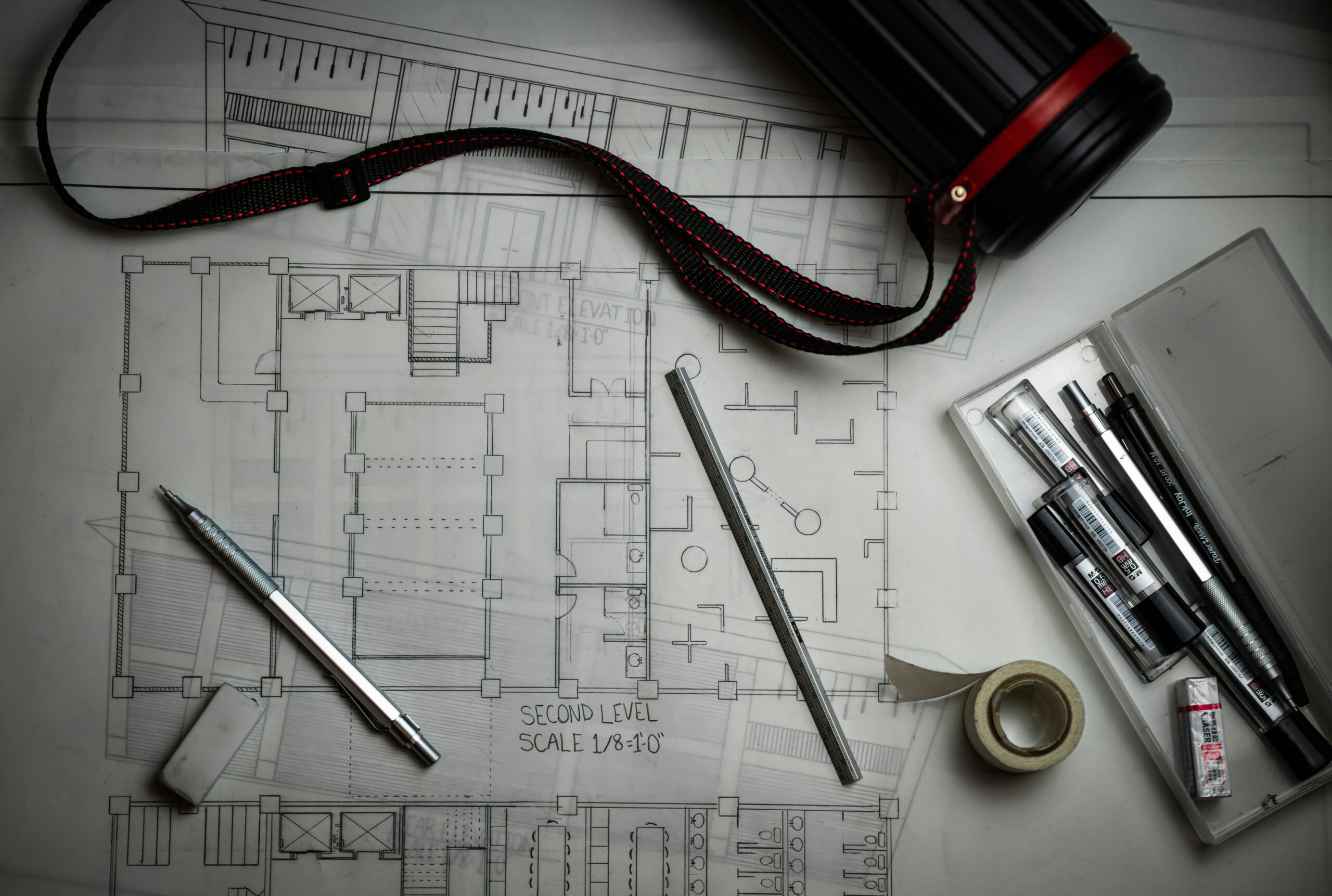 Architectural plans and technical drawing tools representing expert analysis in a property dispute.