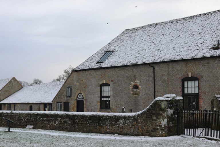 Historic stone building with a snow-covered tiled roof, traditional windows and guttering in winter.